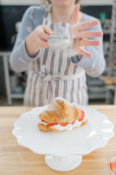 branding photos captured by Columbus photographer of baker sprinkling sugar on a baked good