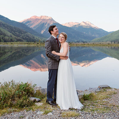 Elopement couple stands by a creek with a mountain in the background in Ouray Colorado