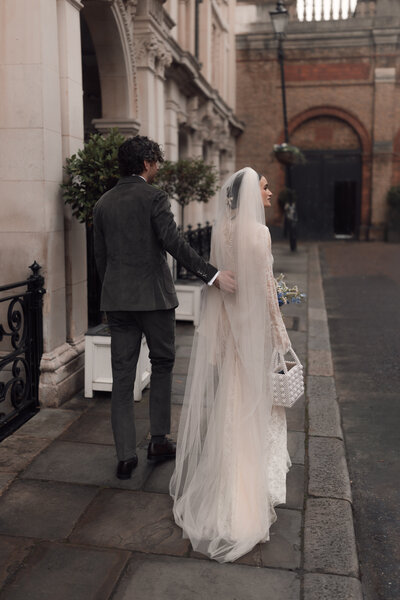 A portrait view of Janice and Bertie walking hand in hand at their wedding ceremony at the Coppa club in the Cotswolds