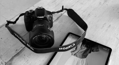 black and white picture of a camera stood next to an iPad