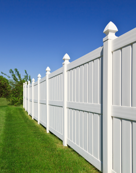 White vinyl fence installed in residential yard by Black Bear Roofing & Exteriors.