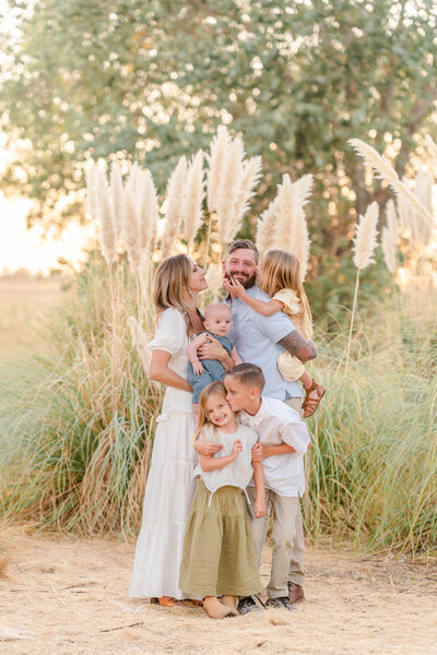 A family photoshoot taken by Bay area photographer shows a family standing ad interacting lovingly in a field of pampas grass.
