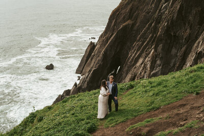 Couple stands on a cliff side on the Oregon Coast during their elopement vows.