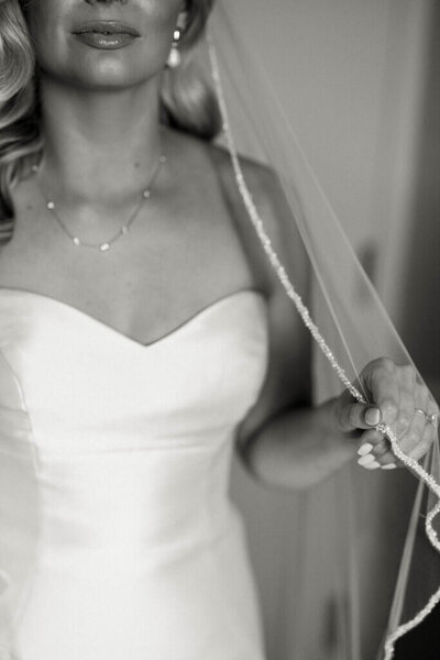 bride holds veil and poses for portrait