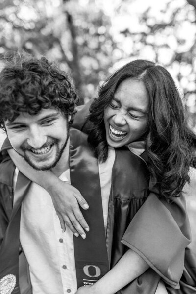 College graduates laughing during a piggy back ride, representing the playful and fun style of Eugene lifestyle photographer Among the Oaks. 