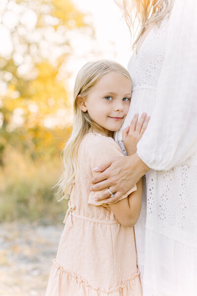 Blonde older sister hugging her mother's pregnant belly