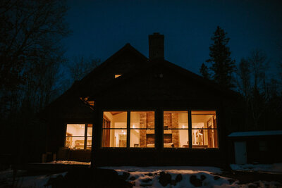 Cabin lit with patio lights at night.