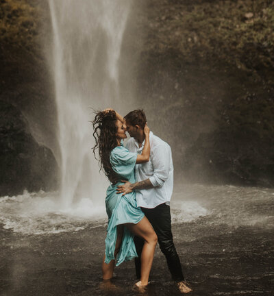 couple holding eachother in front of a waterfall