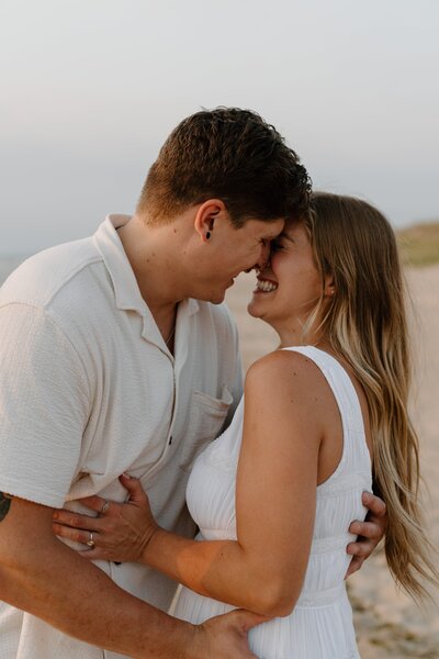 couple holding each other and laughing during beach photoshoot