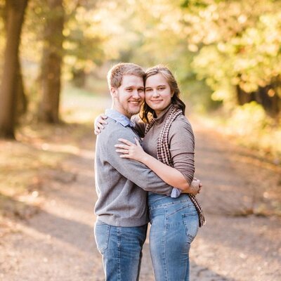 Engaged couple holding each other with their heads together, looking at the camera.