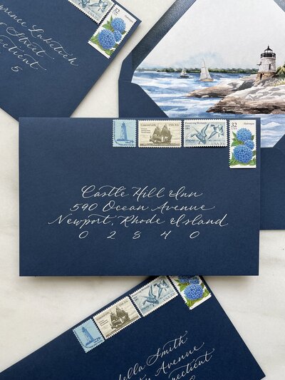 Navy blue wedding invitation envelope with white ink calligraphy and vintage postage stamps for Castle Hill Inn wedding.