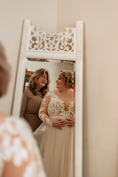 Mother lovingly looking at her daughter in her beautiful wedding dress.