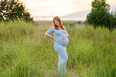 Red-haired woman wearing a blue maternity dress for her Maternity dress for her outdoor maternity photography session in Burlington, Ontario
