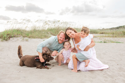 five members of a family with their white dog photographed wearing light blue and white at Hampton Park Charleston SC