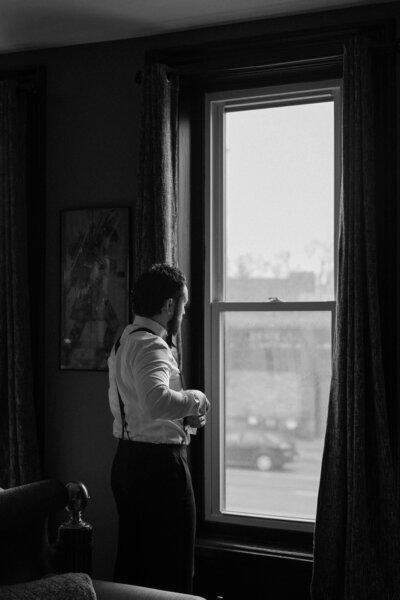 A person putting on a suit and looking out a window 
