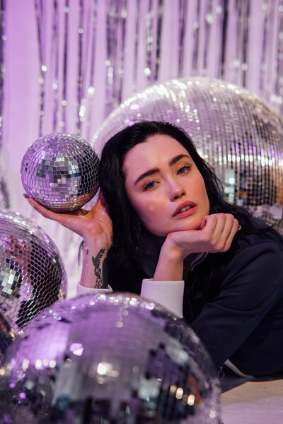 Lady laying between and holding up disco balls