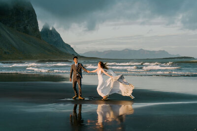 couple running on black sand beach in Iceland for Elopement