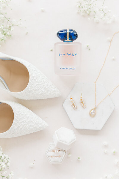 San Antonio wedding photographer captures details of the wedding day by aligning some of the brides wedding day items. This flat lay includes white heels, bride's jewelry, and perfume.