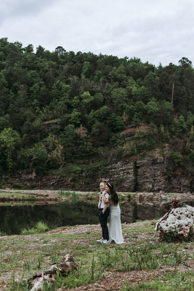 Brides looking out over the Beavers Bend river and hold each other