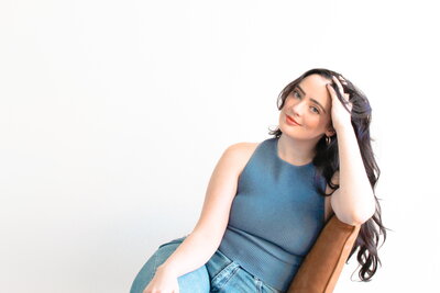 Woman with dark hair smiling on orange chair white background