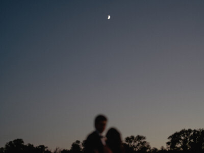 Sky and moon in focus with bride and groom out of focus