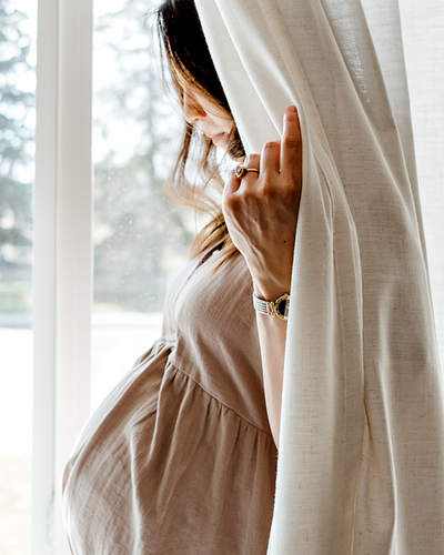 a pregnant woman standing behind a curtain