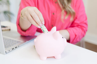 Erika putting dollar bills into a piggy bank