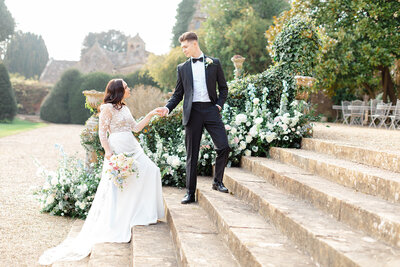Bride and Groom hold hands on the staircase at Brympton house Garden
