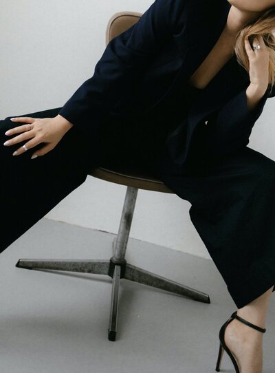 A woman in a black suit seated in a power pose