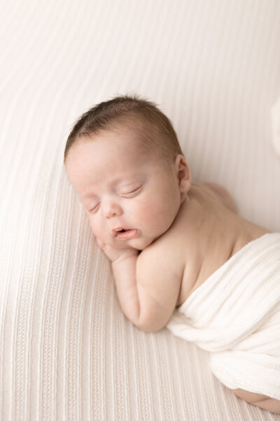 Newborn baby boy wrapped in swaddle blanket