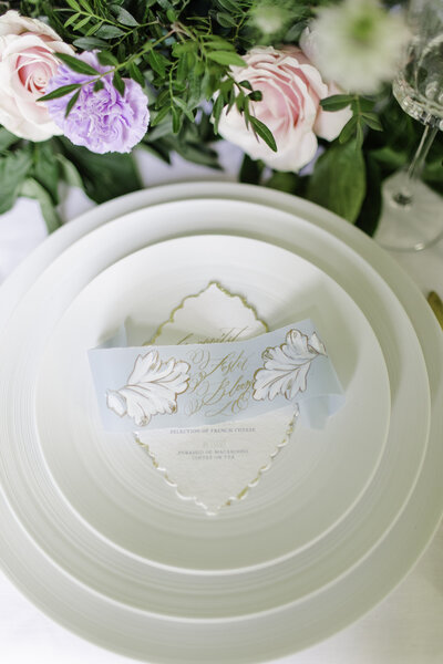 Luxury wedding reception with white china and gold foil menus