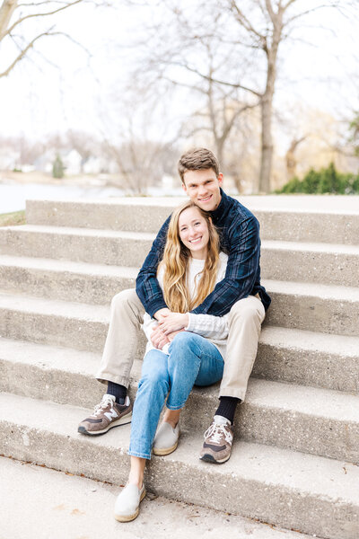 engaged couple embracing while sitting on steps