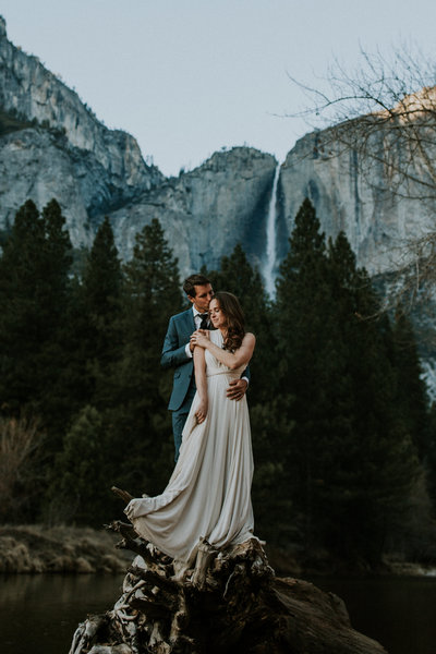 bride and groom embracing with mountains and waterfall in background
