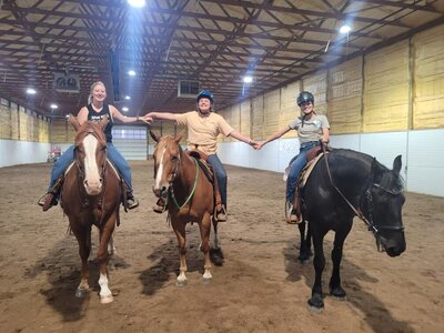 young equestrian enthusiasts holding hands while riding horses, participating in inclusive kids' camps and riding lessons at Spirit's Respite Ranch in Central Alberta