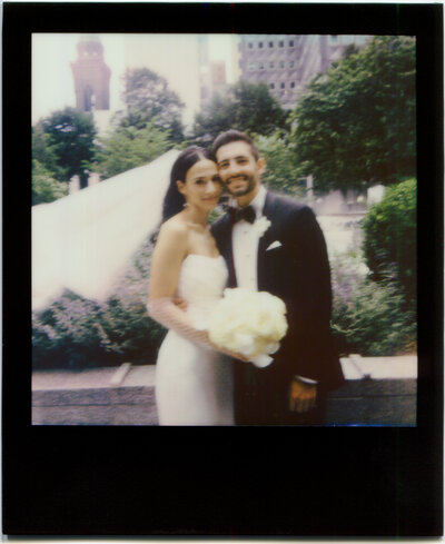 Bride and Groom smile as they post in front of Pittsburgh skyline