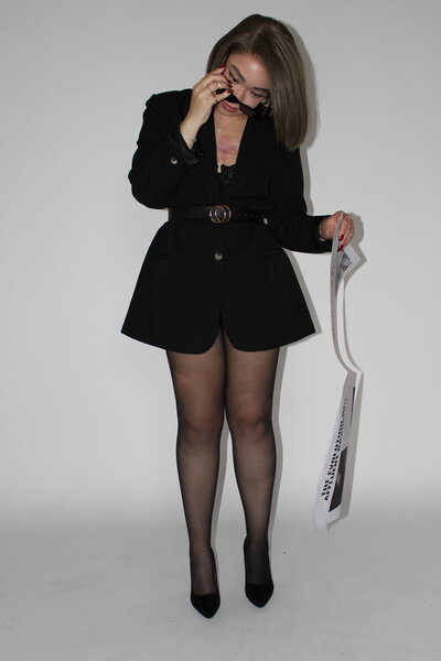 Bri Davis, Founder of Allure Atelier, putting on sunglasses with one hand and newspaper in the other hand