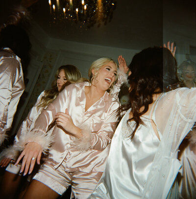 Bride is dancing with bridesmaids in their pajamas as they are getting ready