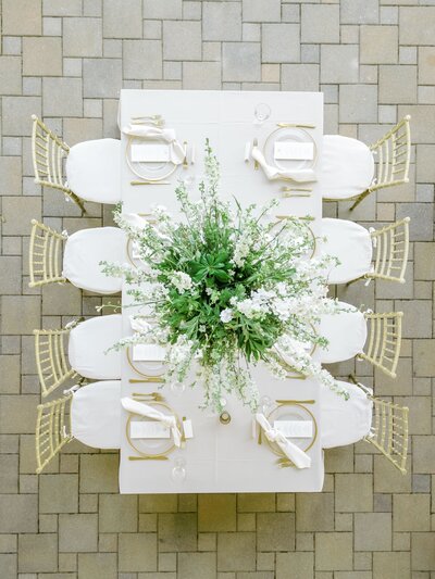 Bird's eye view of a beautifully decorated wedding reception table with a large floral centerpiece,