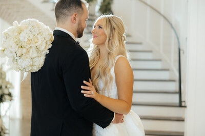 Sophie and Kyle looking at each other in their grand white barn wedding venue.