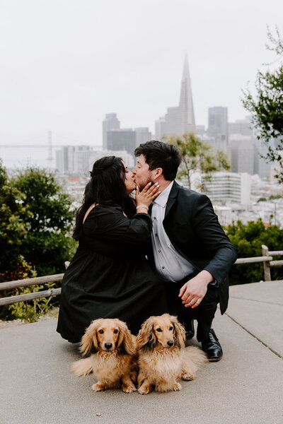 couple kissing with their dogs