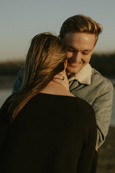 A heartfelt golden-hour moment, captured by a West Michigan wedding photographer. The photo shows a loving couple wrapped in a tender embrace, emphasizing genuine emotion and the warm, natural glow of the setting.