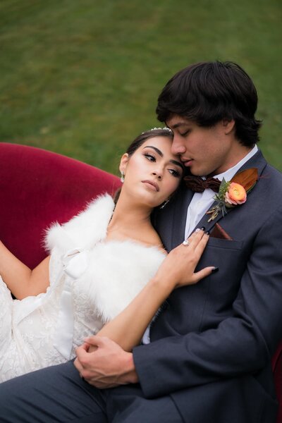 Bride and groom dramatic pose on red velvet couch