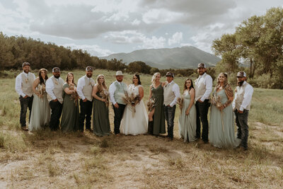 Rusting wedding in Rush Valley, Utah. Bridal party standing in field with mountians in background