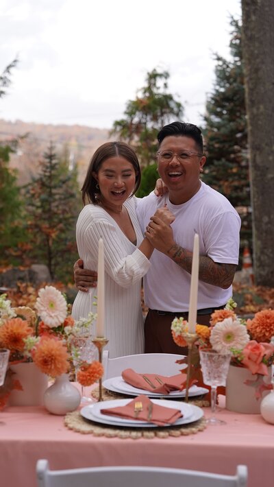 Happy couple celebrating at a fall-themed tablescape with orange and peach florals, styled by Yours Truly, a wedding planner and designer in New Jersey.