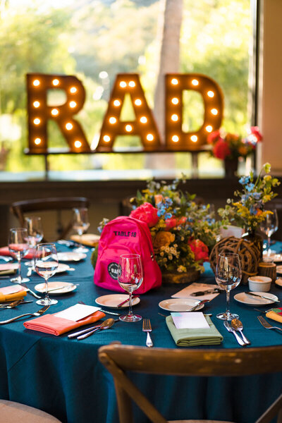 Close up of a groovy and retro floral centerpiece and drink menu for a retro grateful dead themed wedding