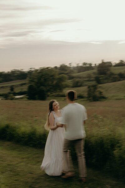 An engaged couple dances around an open field in Iowa City, Iowa.