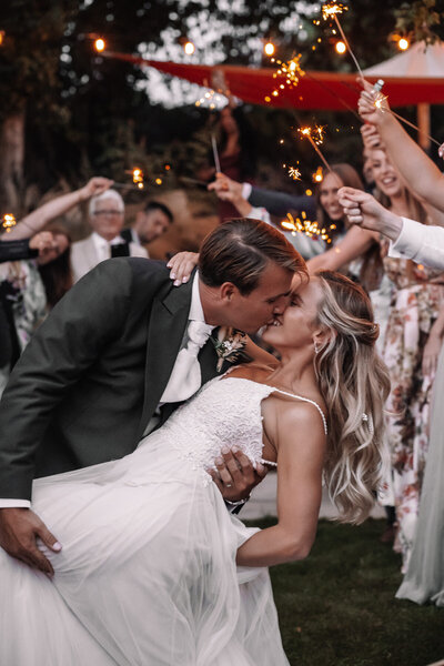 Groom wearing sunglasses and holding brides hand on outdoor steps