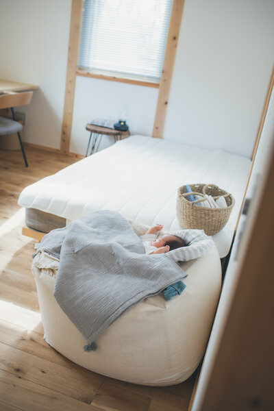 窓の光が差す部屋で新生児の赤ちゃんが寝ている様子