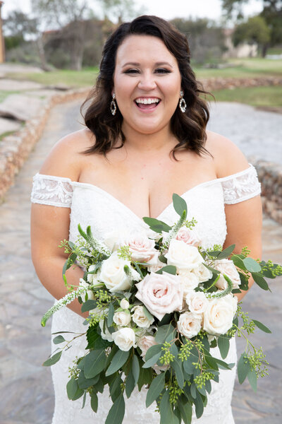 An Austin-based wedding photographer captures a bride's radiant smile as she holds her beautiful wedding bouquet.