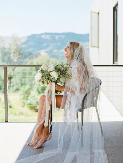 joyful bride getting ready in lace robe and veil